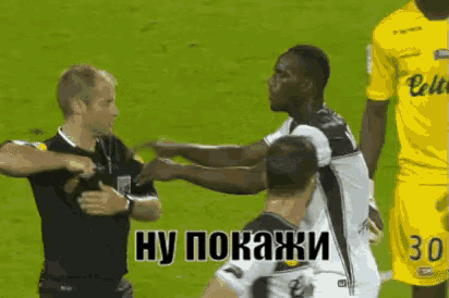a man in a yellow jersey with the number 30 on it is standing next to a referee