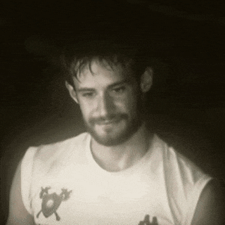 a man with a beard is wearing a white shirt with a picture of a cat on it
