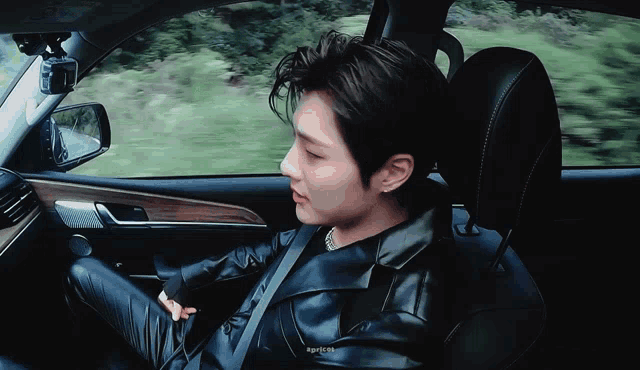 a man in a black leather jacket is sitting in the driver 's seat of a car ..