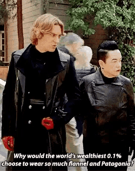 two men are standing next to each other and one of them is wearing a leather jacket .