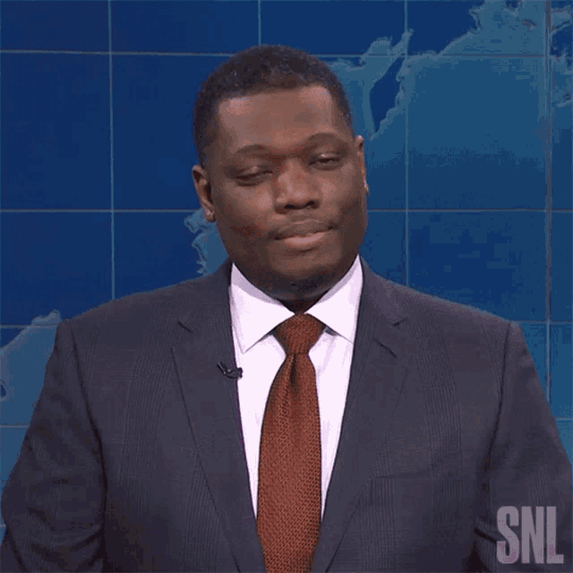 a man in a suit and tie with the snl logo on the bottom