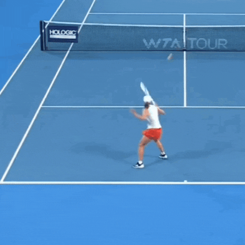 a woman is swinging a tennis racket on a tennis court with a net that says hologic on it