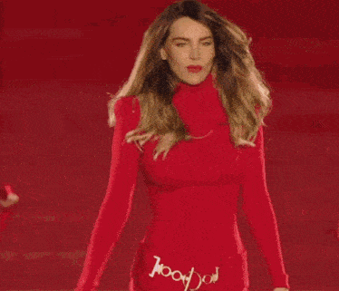 a woman in a red turtleneck sweater is dancing with her arms outstretched