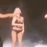 a woman in a swimsuit is dancing on a stage with a man .