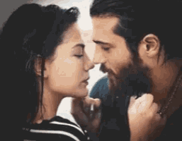 a man and a woman are kissing each other in front of a window .