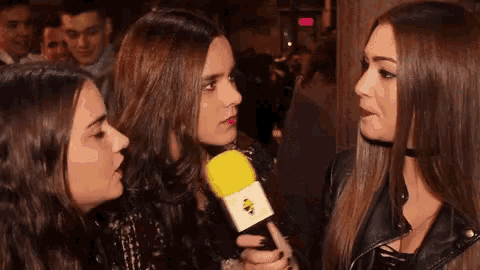 three women are talking to each other while holding a microphone .