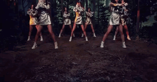 a group of women are dancing in a forest in a blurry photo .