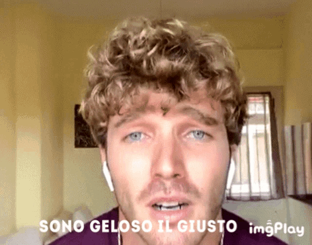 a man with curly hair is wearing headphones and says sono gelosi il giusto