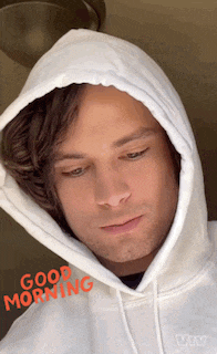 a man wearing a white hoodie says good morning in red letters