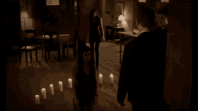 a woman is kneeling down in front of a row of candles