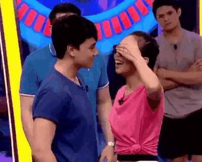 a man and a woman are standing next to each other and the woman is covering her eyes with her hand .