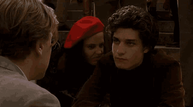 a man wearing a red beret is talking to a woman