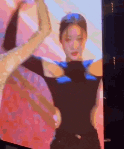 a blurry picture of a woman dancing in front of a pink background .