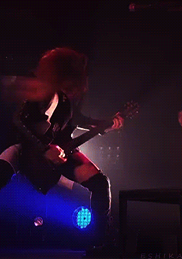 a woman is playing a guitar in a dark room and the word eshika is on the bottom left