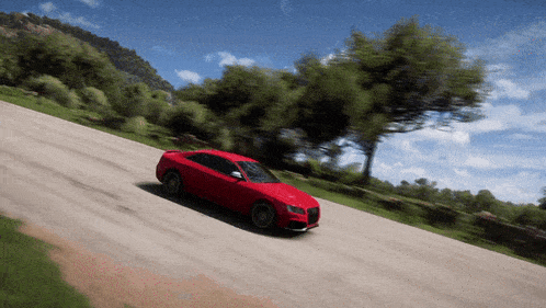 a red car is driving down a dirt road with trees on the side