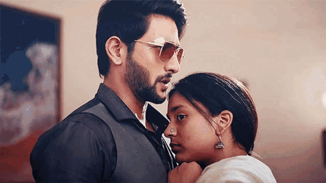 a man and a woman are looking at each other with the man wearing sunglasses