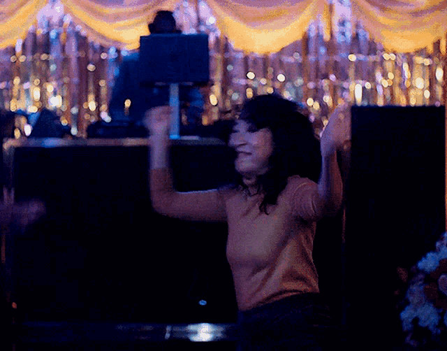 a woman is dancing in a dark room with shimmering lights