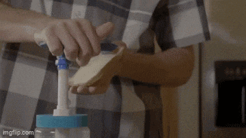 a man in a plaid shirt is making a sandwich with peanut butter and mayonnaise .