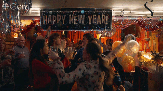 a happy new year banner hangs above a crowd of people