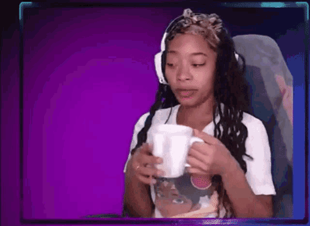 a woman wearing headphones is sitting in a chair and holding a cup of coffee .