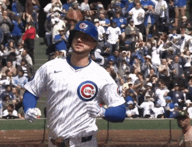 a baseball player wearing a cubs uniform stands in front of the crowd