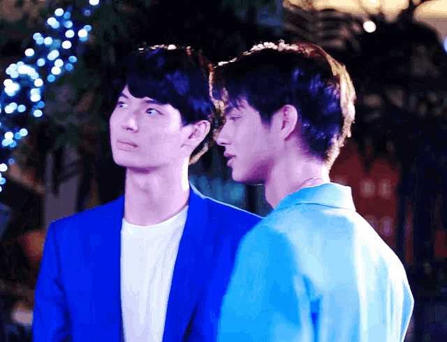 a man in a blue jacket stands next to another man