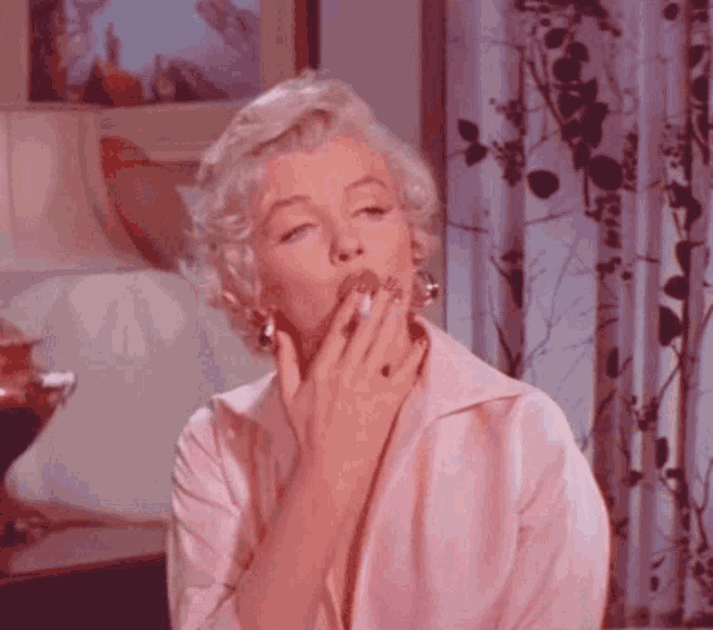 a woman in a pink shirt is covering her mouth