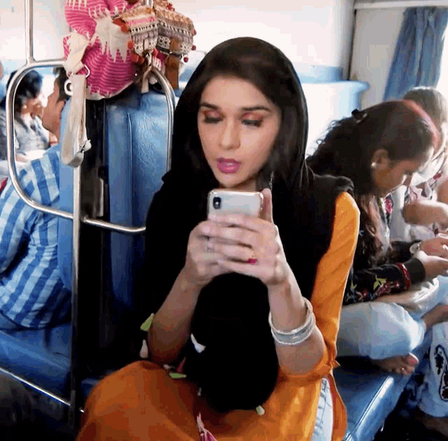 a woman is sitting on a bus looking at her cell phone