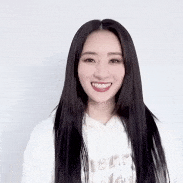a woman with long black hair is wearing a white sweatshirt and smiling .