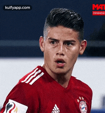 a close up of a soccer player wearing a red jersey looking at the camera .