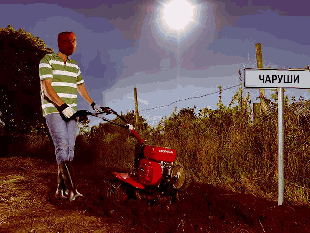 a man wearing a mask is plowing a field with a honda branded tractor