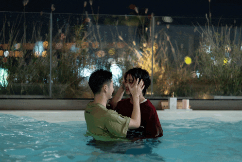 a man in a green shirt that says ' i love you ' on it kisses another man in a red shirt