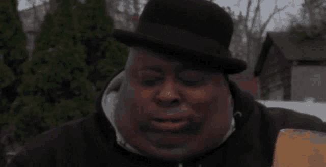 a man wearing a black hat and a black hoodie is holding a shovel