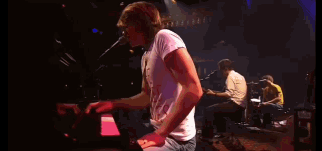 a man in a white shirt is playing a piano on stage
