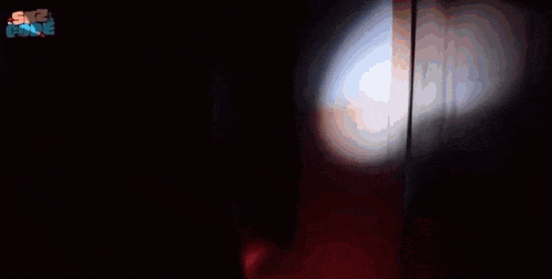 a close up of a red object with a white light coming out of it in the dark .