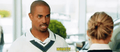 a man in a white polo shirt is talking to a woman in a car showroom .