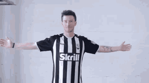 a man is wearing a black and white striped shirt that says skrill