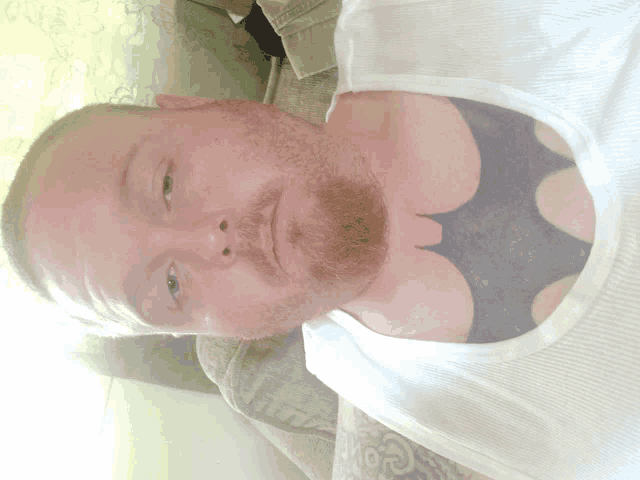 a man with a beard and a batman tattoo on his chest