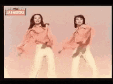 two women are dancing in front of a sign that says las chicas