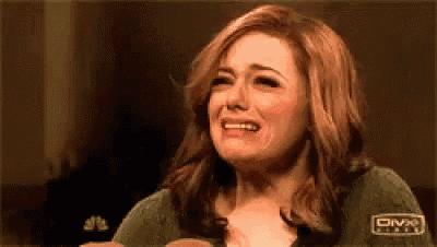 a woman is crying while wearing a green sweater that says diva