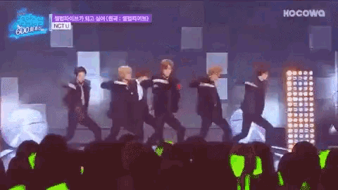 a group of people are dancing on a stage in front of a crowd and a sign that says kocowa on it