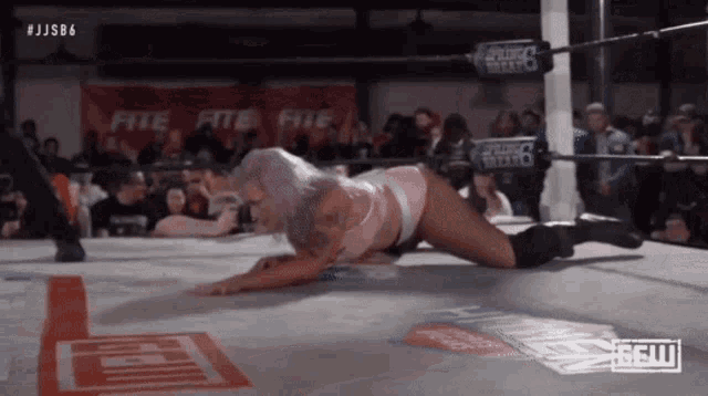 a woman is laying on the ground in a wrestling ring with a sign that says jjsb6 on it