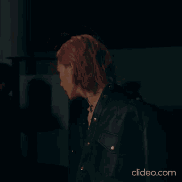 a man with red hair is wearing a black leather jacket and a black shirt .