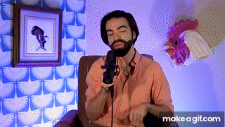a man with a beard is sitting in front of a microphone