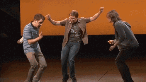 three men are dancing on a stage and one of them is wearing a shirt that says ' a ' on it