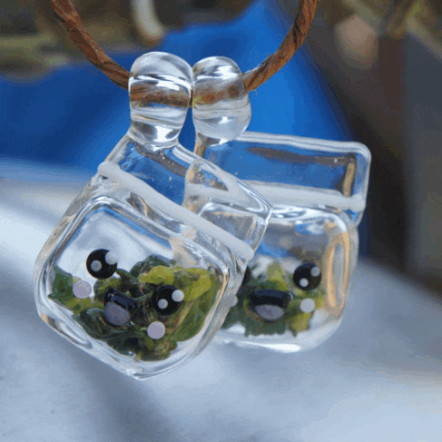 a pair of clear glass pendants with a frog inside
