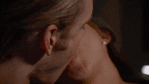 a man and a woman are kissing in a dark room .