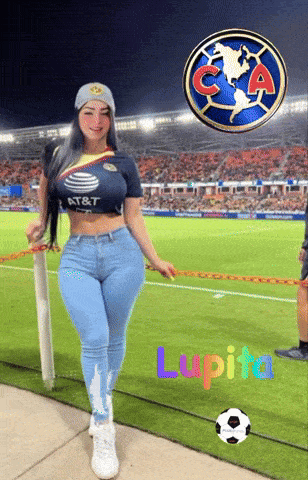 a woman wearing a shirt that says at & t is standing in front of a soccer field