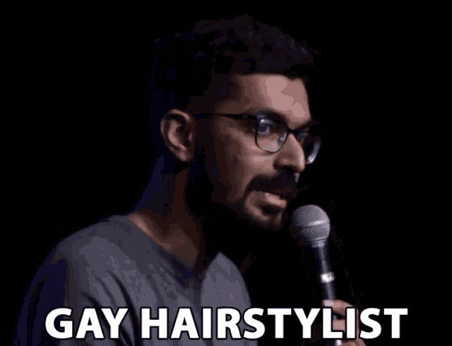 a man wearing glasses is holding a microphone and saying gay hairstylist