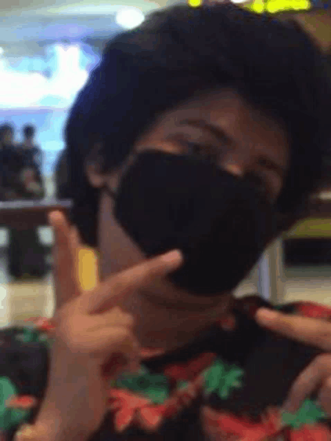 a person wearing a black face mask is giving a peace sign